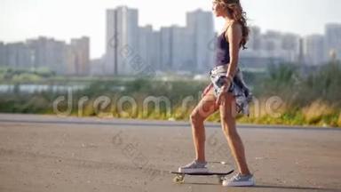 年轻女孩骑着滑板，停下来，<strong>拿起</strong>它，看着相机